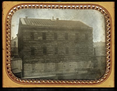 Das Stadtgefängnis an der südöstlichen Ecke der Sixth und Chestnut Streets. Kleine, hölzerne Hütten stehen in der Nähe des Gefängnisses sowie Zäune. Einige Architektur ist im Hintergrund zu sehen von Thomas M. Easterly